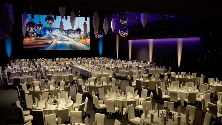 Banquet setup: round tables with white tablecloths, mirror balls and hanging lamps under a starry ceiling